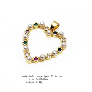 Detail view of a gold heart pendant with colorful zircon stones and pearl inlay