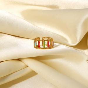 Close-up of 18K gold plated hollow ring with colorful enamel drip on champagne satin