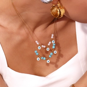 Detail of layered gold necklace with turquoise beads, pearls and evil eye pendant