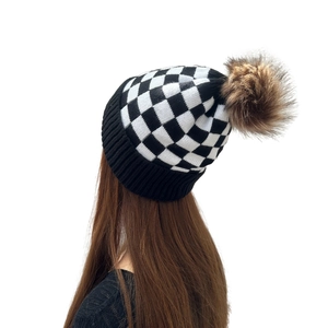 Women's checkerboard knit beanie with a brown faux fur pom pom for winter warmth