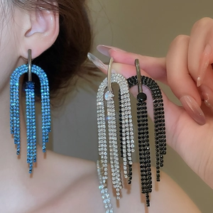 Détail de boucles d'oreilles à pompons avec strass étincelants en bleu et argent