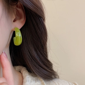 Close-up of green resin hoop earring with cloud texture on female model's ear