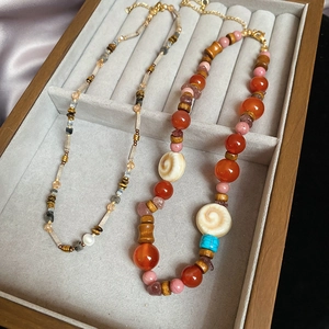 Detail of bohemian necklace featuring natural agate, wood beads, and turquoise in a tray