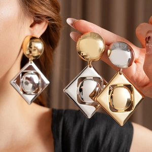 Macro detail of geometric gold and silver drop earrings with circular and diamond elements