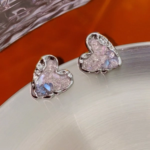Détail de boucles d'oreilles cœur avec cadre en métal argenté et cristaux roses