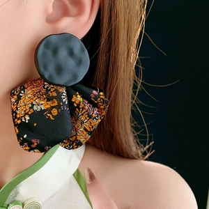 Close-up of black metal studs with vibrant floral fabric embroidery on a female model