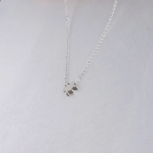 Close-up of a silver stainless steel puzzle piece pendant necklace on a textured surface