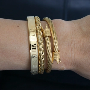 Detailed view of three-piece gold stacked bracelets featuring roman numerals and crown design