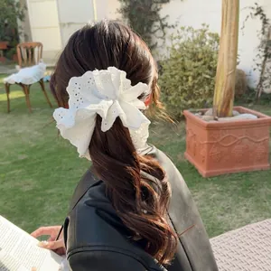Elegant white lace scrunchie with floral embroidery shown on hair in outdoor sunlight
