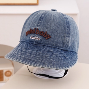 Close-up of embroidered letters on denim baby sun hat with windproof strap detail