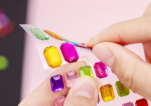 Close-up of hands peeling colorful acrylic rhinestone stickers for DIY projects