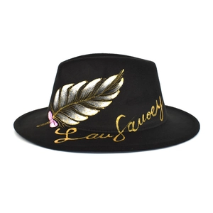Detail of hand-painted gold and silver feather motif on a black wool fedora hat