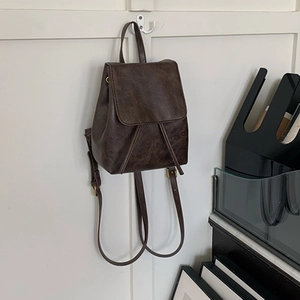 Dettaglio dello zaino vintage in ecopelle marrone con patta e coulisse appeso al gancio