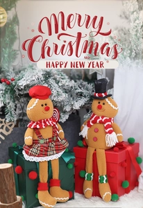 Detail of gingerbread plush couple with hats and scarves sitting on festive gift boxes
