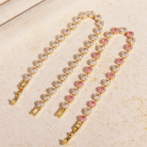 Close-up of square-cut pink and white zircon tennis bracelets with golden claw settings