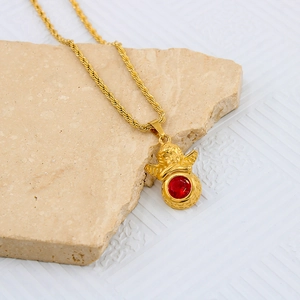 Close-up of golden angel pendant with red zircon stone on vintage twisted rope chain necklace