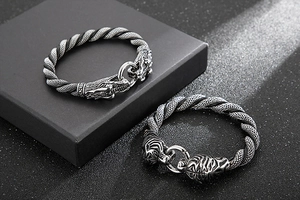 Detailed close-up of tiger and dragon head buckles on braided stainless steel bracelets