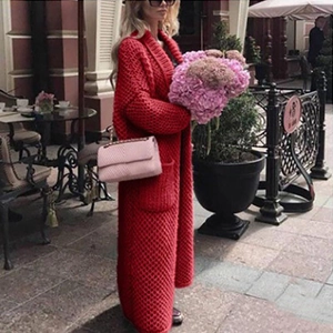 Detailed view of red long knit cardigan paired with a pink chain flap crossbody bag
