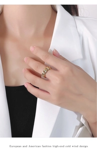 Close-up of a gold chain link ring worn by a model in a white blazer for a luxury look