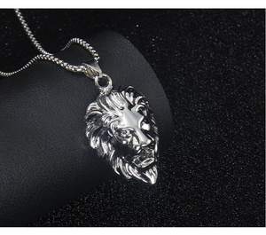 Detailed close-up of a silver lion head pendant necklace with 3D relief on dark background