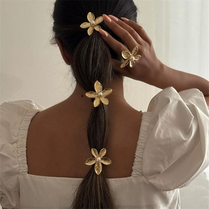 Elegant gold metal flower hair accessories set with pearls on a model's ponytail