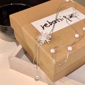 Gros plan d'un collier de perles avec pendentif étoile sur une boîte cadeau rustique