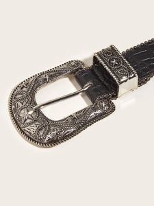 Detail of western vintage belt showing silver engraved buckle and black crocodile texture