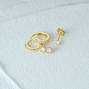 Macro shot of 3-piece gold-plated earring set with cubic zirconia on white stone