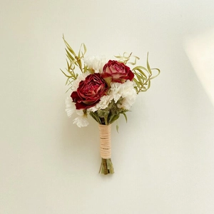 Macro shot of a dried flower boutonniere with red roses, white carnations, and twine wrap