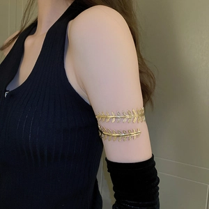 Detail view of a gold leaf arm cuff with delicate layered foliage on a female model