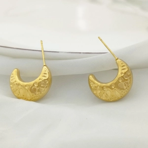 Close-up of golden U-shaped earrings with intricate hollow embossed floral patterns