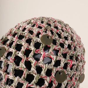 Détail du bonnet en maille tissée à la main avec paillettes dorées et fils de couleur