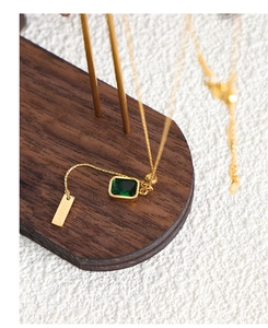 Close-up of gold chain necklace with emerald zircon pendant and engraved BABY tag
