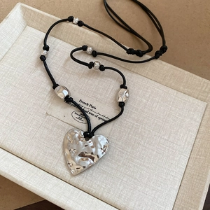 Silver wrinkled heart dachshund pendant necklace with black wax rope cord on beige display