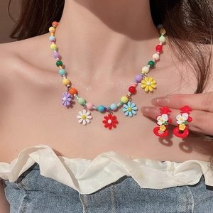 Detail of colorful beaded necklace with resin flowers and red character earrings