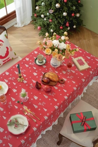 Detailed view of red Christmas tablecloth featuring white ruffles and reindeer patterns