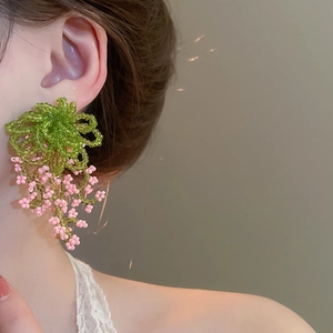 Detail of handmade flower cluster beaded earrings with green and pink tassels on model