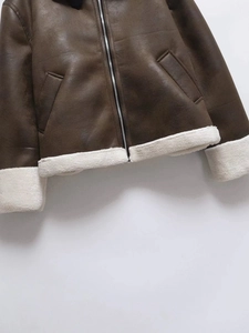 Detail of brown faux suede jacket hem showing white faux shearling lining and metal zipper