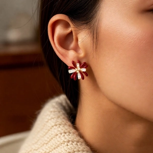 Detail of red flower stud earrings with zirconia stones worn by a fashion model