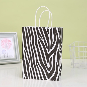 Detail of zebra print kraft paper gift bag with white twisted rope handles on table