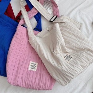 Detail of pleated canvas tote bag fabric with adjustable strap and brand woven label