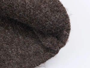 Détail macro du tissu tricoté marron foncé montrant la texture épaisse des fibres
