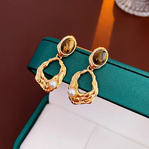 Detail of vintage gold-plated lava earrings featuring oval tiger eye and white pearl drops