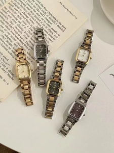 Kollektion eleganter quadratischer Quarzuhren mit Metallarmband auf einem Vintage-Buch