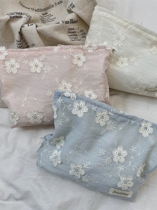Set of three embroidered floral cosmetic bags in pink, white, and blue cotton fabric
