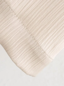 Gros plan sur la texture du tissu côtelé beige clair et les coutures de finition précises