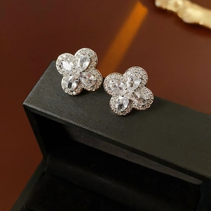 Gros plan de boucles d'oreilles trèfle en argent avec zircons sur un écrin à bijoux