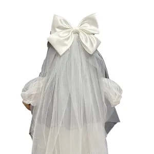 Elegant white satin bow hair clip with tiered sheer tulle bridal wedding veil for photography