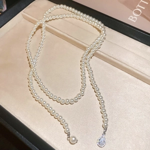 Macro shot of pearl beaded necklace featuring a sparkling diamond teardrop pendant