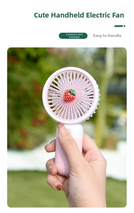 Close-up of pink strawberry portable mini fan with ergonomic handle in outdoor setting